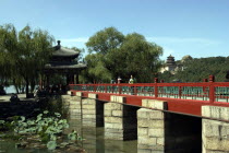View of a bridge on brick supports with the complex buildings visible through trees