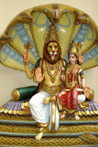 Colurful statue of a lion headed God with four arms and a female figure sitting on his lap at an Indian Hindu Temple
