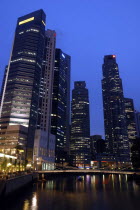 City skyscrapers illuminated at night with bridge over water in the foreground