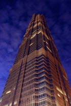 Angled view looking up at the Hyatt Hotel skyscraper illuminated at dusk