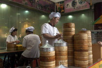 Restaurant with stacked bamboo steamers and workers dressed in white