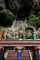 View looking up the steep teps toward the Cave entrance with colourful statues atop columned archway in the foreground