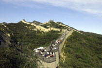 View alongside a section of the wall which runs through the hilly green landscape covered in tourists