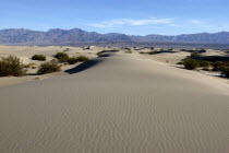 View over sand dunes in the desert landscape toward rocky horizon