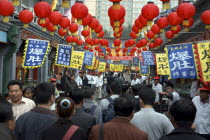 Busy street scene with red lanterns hanging in rows overhead