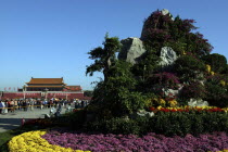 Gate of Heavenly Peace or Tiananmen. View over rockery and flowerbeds toward crowds gathered outside the gate building