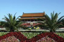 Gate of Heavenly Peace or Tiananmen. View over flowerbeds and palms toward the gate building facade with large portrait of Mao