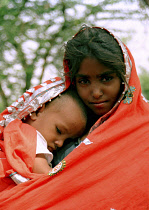 Portrait of a young girl wrapped in a red shawl with her younger brother