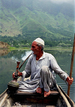 Nagin Lake. Man sitting in boat smoking a Hookah pipe