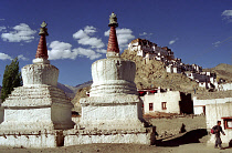 Tikse Gompa. Twin red and white stupas with hilltop architecture beyond