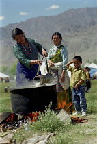 Woman heating milk in large pot at the 14th Dalai Lamas birthday celebrations