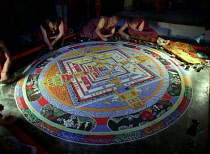 Several monks painting decorative patterns for the Pujar ceremony  and the making of a spiritual Mandala