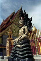 Seated Buddha statue outside elaborately decorated temple