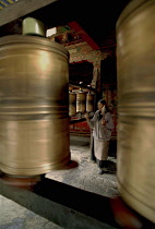 Jokhang Temple. Worshipper walking clockwise spinning prayer wheels with offerings of prayers for the benefit of mankind.