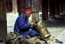 Man repairing prayer wheel as Penance at the Jokhang Temple