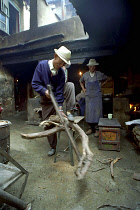 Elderly man cutting firewood for the kitchen in a courtyard