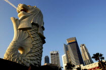 Merlion statue spouting water in evening light with city skyscrapers beyond