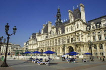 Hotel de Ville overlooking pedestrianized square with umbrellas and chairs