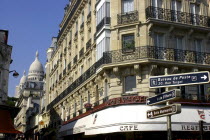 Corner cafe  and street signs with the domes of the Sacre Coeur in the distance