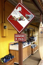 Surf and dive shop sign with cartoon diver feeding a shark