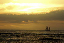 Sunset over the sea with passing sail boat