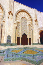 Hassan II Mosque courtyard with mosaic star shaped brickwork fountain and archway beyond