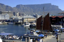 View over the waterfront area with busy tourist boats and Table Mountain in the background