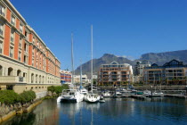 View of the waterfront with moored boats and buildings against a backdrop of mountains