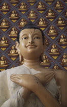Wat Chayamangkalaram.  Detail of Buddha figure with hands crossed over chest.  Wall behind covered with small raised seated Buddha figures painted gold.  Also known as Wat Buppharam.