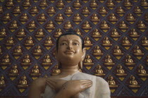 Wat Chayamangkalaram.  Detail of Buddha figure with hands crossed over chest.  Wall behind covered with small raised seated Buddha figures painted gold.  Also known as Wat Buppharam.