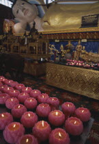 Wat Chayamangkalaram.  Interior.  Part view of  reclining Buddha with pink lighted candles in the shape of lotus flowers in the foreground. Also known as Wat Buppharam.