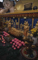 Wat Chayamangkalaram.  Interior.  Part view of  reclining Buddha lying behind smaller figures covered in gold leaf and lighted candles in the shape of lotus flowers. Also known as Wat Buppharam.