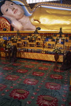 Wat Chayamangkalaram.  Interior with part view of 32 metre long reclining Buddha lying behind display of various smaller figures and statues.