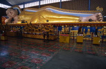 Wat Chayamangkalaram.  Interior with 32 metre long reclining Buddha lying behind display of various smaller figures and statues.