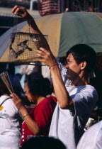 Goddess of Mercy Temple  also known as Kuan Yin Teng.  Man releasing caged birds to attain merit for the afterlife.