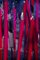 Goddess of Mercy Temple  also known as Kuan Yin Teng.  Close view of large  pink burning sticks of incense with worshippers partly seen behind.