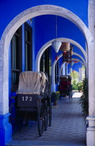 Cheong Fatt Tze Mansion. View through series of covered archways running along exterior of house framing old rickshaws and hanging Chinese lanterns.