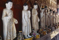 Dharmikarama Burmese Temple.  Interior with large standing Buddha figure with raised hand in gold painted robe and ornate carved gold panel behind.
