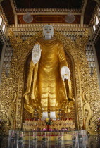 Dharmikarama Burmese Temple.  Interior with large standing Buddha figure with raised hand in gold painted robe and ornate carved gold panel behind.