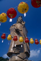 Bronze statue of Kuan Yin or Avalokiteshvara  the male Bodhisattva  a future Buddha representing the force of creation.  Chinese New Year lanterns in foreground.