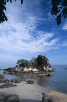 Batu Ferringhi or Foreigners Rock rising out of shallow water beside beach of the same name.