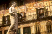 Piazza della Erbe.  Detail of the Fountain of Madonna  statue of female figure in crown in front of building with painted facade  green window shutters and balcony.