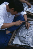 Tha Phae Road.  Young man working on metal work relief picture.Asian Prathet Thai Raja Anachakra Thai Siam Southeast Asia Immature Male Men Guy Siamese Male Man Guy Young Unripe Unripened Green