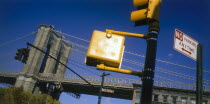 Part view of Brooklyn Bridge with road sign and traffic lights in the foreground.