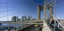 Lower Manhattan.  Post September 11 skyline from Brooklyn Bridge intersected by tension wires with traffic and pedestrians crossing.