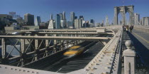 Lower Manhattan.  Post September 11 skyline from Brooklyn Bridge with traffic and pedestrians crossing.