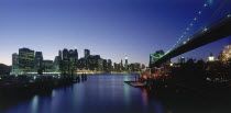 Lower Manhattan.  Post September 11 skyline from Brooklyn illuminated at night with Brooklyn Bridge in the foreground.