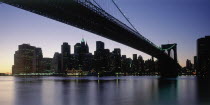 Lower Manhattan.  Post September 11 skyline from Brooklyn illuminated at night with Brooklyn Bridge in the foreground.