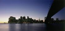 Lower Manhattan.  Post September 11 skyline from Brooklyn illuminated at night with Brooklyn Bridge in the foreground.