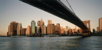 Lower Manhattan.  Post September 11 skyline from Brooklyn in evening light with underside of Brooklyn         Bridge in the foreground.